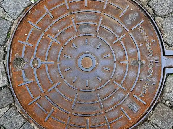 Plaque d’égout en fonte sur des pavés